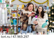 Female friends client scanning QR code on package laundry fabric softener and tile cleaner. Стоковое фото, фотограф Яков Филимонов / Фотобанк Лори