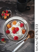 Creamed cottage cheese with raspberries. An easy healthy breakfast. A bowl filled with grainy, creamy cottage cheese is garnished with bright yellow and red raspberries. Top view. Стоковое фото, фотограф Оксана Медведева / Фотобанк Лори