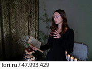 An Enchanting Sorceress is deeply engrossed in reading a Spellbook surrounded by swirling, Mystical Smoke. Стоковое фото, фотограф Anastasy Yarmolovich / Фотобанк Лори