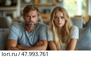 A man and woman sit side by side on a couch, displaying looks of frustration and concern while engaged in a serious discussion. Стоковое AI-изображение, AI-художник Данила Большаков / Фотобанк Лори
