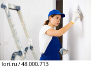 Female plasterer smoothing stucco on wall with finishing trowels. Стоковое фото, фотограф Яков Филимонов / Фотобанк Лори