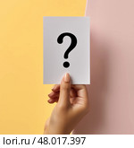 Hand holding a question card with a minimalist design on a colorful background. Рука, держащая карточку со знаком вопроса, с минималистичным дизайном на цветном фоне. Стоковое AI-изображение, AI-художник Katsiaryna Repich / Фотобанк Лори