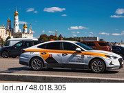 Russia, Moscow, April 28, 2025. Taxi business. A yellow taxi car in motion against the background of the Kremlin in the center of the capital. A trip to the famous sights of Moscow. Редакционное фото, фотограф Photojuli / Фотобанк Лори