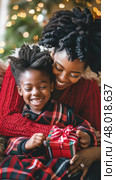 A mother and son happily unwrap a Christmas gift together in a warm, decorated room. Стоковое AI-изображение, AI-художник Данила Большаков / Фотобанк Лори