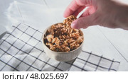 A woman's hand takes a peeled walnut kernel from a bowl filled with walnuts, preparing to enjoy a nutritious and delicious snack rich in protein and healthy fats. Стоковое видео, видеограф Ольга Ильина / Фотобанк Лори