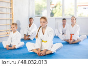 Family during group karate training with trainer in gym performs stretching of muscles by performing butterfly exercise. Стоковое фото, фотограф Яков Филимонов / Фотобанк Лори