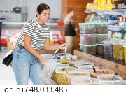 Female shopper scooping pickled olives in grocery store. Стоковое фото, фотограф Яков Филимонов / Фотобанк Лори
