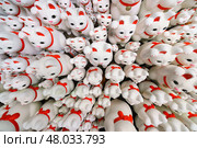 Tokyo, Japan - Sep 30 2024, A close-up view of many multi-sized white beckoning cat figure of Maneki neko with red ears and noses displayed at Gotokuji Temple, without people, at daytime, Tokyo, Japan. Стоковое фото, фотограф Сергей Богомяко / Фотобанк Лори
