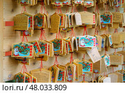 Tokyo, Japan - Sep 30 2024, Close-up view of a wall hung with wooden prayer plaques with various images and inscriptions at Gotokuji Temple, Tokyo, Japan. Редакционное фото, фотограф Сергей Богомяко / Фотобанк Лори