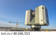 Geodesic 3D scanner against background of blue sky and construction crane. Implementation of geodetic accurate measurements during construction. Стоковое фото, фотограф Скрипачев Антон / Фотобанк Лори