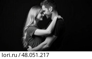 Beautiful couple in love hugging against black background. Studio black and white portrait photo of a girl blondes and a guy with short hair. Valentine's day. Loving married couple. Стоковое AI-изображение, AI-художник Sergey Grishin / Фотобанк Лори