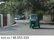 Зеленый тук-тук едет по тихой улице днем ​​в Галле, Шри-Ланка.  Green Tuk-Tuk Driving Down Quiet Street in Daylight in Galle, Sri Lanka (2018 год). Редакционное фото, фотограф Соболева Наталия / Фотобанк Лори