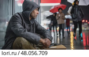 Homeless man sitting on sidewalk begging in rain at night. Стоковое AI-видео, аниматор Юрий Поздников / Фотобанк Лори