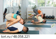Young couple practicing acro yoga on mat in studio together, flexibility class workout. Стоковое фото, фотограф Яков Филимонов / Фотобанк Лори