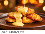 Crispy, golden chicken nuggets topped with gooey cheese sauce create a mouthwatering snack. The perfect comfort food, these nuggets offer a delightful crunch and savory flavor. Стоковое AI-изображение, AI-художник Nart / Фотобанк Лори