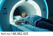 Мужчина средних лет лежит внутри аппарата МРТ. Стоковое AI-изображение, AI-художник Илья Старков / Фотобанк Лори