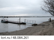 Причал на берегу реки с лодкой и человеком. Редакционное фото, фотограф Станислав Подольский / Фотобанк Лори