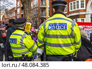 Law enforcement presence at a street protest ensuring safety. London, UK, 16 March 2024. Редакционное фото, фотограф Zydrius Tartenis / Фотобанк Лори
