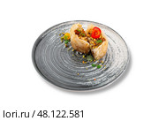 Elegant phyllo pastry roll filled with chopped nuts, served on a modern ceramic plate, decorated with edible flowers and mint for a fine dining presentation. Стоковое фото, фотограф Aleksandr Gavrilychev / Фотобанк Лори