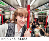 Middle-aged woman enjoying a subway ride while documenting her travel adventure in an urban setting. Стоковое фото, фотограф Кривошеина Елена Леонидовна / Фотобанк Лори