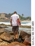 Surfer Walking on Rocks Along the Beach, Embracing the Spirit of Adventure and Freedom. Стоковое фото, фотограф Женя Канашкин / Фотобанк Лори