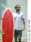 A surfer riding the waves with a bright red surfboard on a beautiful summer day at the beach. Стоковое фото, фотограф Женя Канашкин / Фотобанк Лори