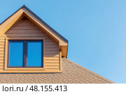 House Exterior. Roof Window. Second floor among blue sky. Mansard attic. Newly build houses. Gable roof with skylight, asphalt roofing, shingles. Residential Home. Vinyl Siding. Polymeric roof-tiles. Стоковое AI-изображение, AI-художник Марина Демидюк / Фотобанк Лори