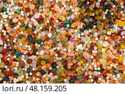 Vibrant mosaic of polished jewels, gleaming minerals, and lustrous beads. A dazzling array of organic shapes and rich hues, perfect for luxurious textures or decorative backdrops. Стоковое фото, фотограф Татьяна Терехина / Фотобанк Лори