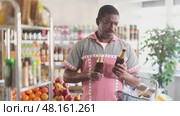 African man hold bottle and choose alcohol beer bottle in store. Стоковое видео, видеограф Яков Филимонов / Фотобанк Лори