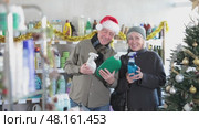 Happy elderly couple choosing detergent and window cleaning spray in supermarket before celebrating Christmas. Стоковое видео, видеограф Яков Филимонов / Фотобанк Лори