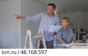 Little son with father together checking blueprints before renovating a room. Стоковое видео, видеограф Яков Филимонов / Фотобанк Лори