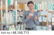 Careful young woman holding pills of paracetamol for purchase in drugstore. Стоковое видео, видеограф Яков Филимонов / Фотобанк Лори