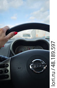 Левая женская рука лежит на рулевом колесе автомобиля Nissan крупным планом. На фоне голубого неба с белыми облаками. Редакционное фото, фотограф Юлия Дубинина / Фотобанк Лори