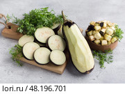 Whole eggplant with peel removed, eggplant cubes and slices soaked in salt on a gray textured background. Methods for removing bitterness from eggplant. Стоковое фото, фотограф Ольга Лепёшкина / Фотобанк Лори