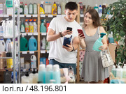 Couple buyer scans qr code on tile cleaner spay label. Стоковое фото, фотограф Яков Филимонов / Фотобанк Лори