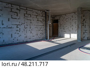 The interior space features bare walls with cement blocks, unfinished flooring, and visible electrical conduits, highlighting construction progress. Стоковое фото, фотограф Данила Большаков / Фотобанк Лори