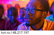 A man passionately shares ideas while captivated youths listen attentively in vibrant lights. Стоковое AI-изображение, AI-художник Данила Большаков / Фотобанк Лори