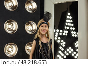 A joyful six-year-old girl dressed in a chic outfit stands confidently in a captivating studio filled with bright lights. She showcases her modeling skills with flair and enthusiasm. Стоковое фото, фотограф Aleksandr Golubev / Фотобанк Лори