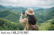 Женщина фотографирует горные пейзажи на смартфон во время похода. Стоковое AI-изображение, AI-художник Илья Горшков / Фотобанк Лори