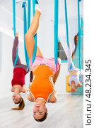 Girl doing inverted king pigeon aerial yoga pose in suspended hammock. Стоковое фото, фотограф Яков Филимонов / Фотобанк Лори