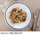 on plate,portion of stewed barley porridge with fried lard, complemented by glass of red wine and pickled cucumbers. Стоковое фото, фотограф Яков Филимонов / Фотобанк Лори