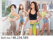 Attractive female dancers in high heels training strip plastic movements during dancing around chair in dance hall. Стоковое фото, фотограф Яков Филимонов / Фотобанк Лори
