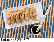 Boiled Yaki Gyoza served in plate with special sauce and chopsticks. Стоковое фото, фотограф Яков Филимонов / Фотобанк Лори