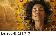 A woman lies on a yellow bedspread with a mandala pattern. She has her eyes closed and looks relaxed. Стоковое AI-изображение, AI-художник Данила Большаков / Фотобанк Лори