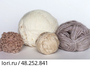 Different types of wool yarn for hand knitting in beige colors on white background. Merino wool, wool-acrylic blend, boucle yarn in balls and skeins. Knitting as hobby. DIY concept. Close-up. Front view. Стоковое фото, фотограф Виктория Катьянова / Фотобанк Лори
