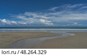 The stream winds along the sandy beach, flows into the ocean. Balls of sand bubbler crabs are visible on the sand. The waves are foaming. Blue sky, clouds. Malaysia. Borneo. Kota Kinabalu. Стоковое фото, фотограф Вера Ивановна Кубарева / Фотобанк Лори