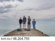 Мужчина с тремя детьми ловит рыбу на пирсе у Черного моря. Адлер. Сочи. Краснодарский край (2025 год) Редакционное фото, фотограф Юлия Кутыгина / Фотобанк Лори