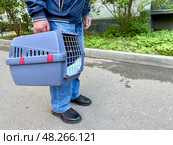 An elderly man holds a cat in a carrier. Pet transportation, traveling with a pet. A close friend of an elderly man. Стоковое фото, фотограф Терехова Марина / Фотобанк Лори