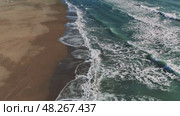 Turquoise ocean waters generating white foam, gentle waves cascading over pristine sandy shore under bright sunlight, revealing tranquil tropical seascape. Стоковое видео, видеограф ILIA GOROKHOV / Фотобанк Лори
