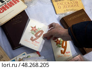 Женщина берет старую советскую открытку с поздравлением с Днем 9 мая в городе Москве, Россия. Редакционное фото, фотограф Николай Винокуров / Фотобанк Лори